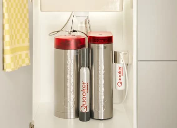 Braun, roter Wasserfilter und zwei Edelstahlflaschen in einem weißen Küchenschrank.