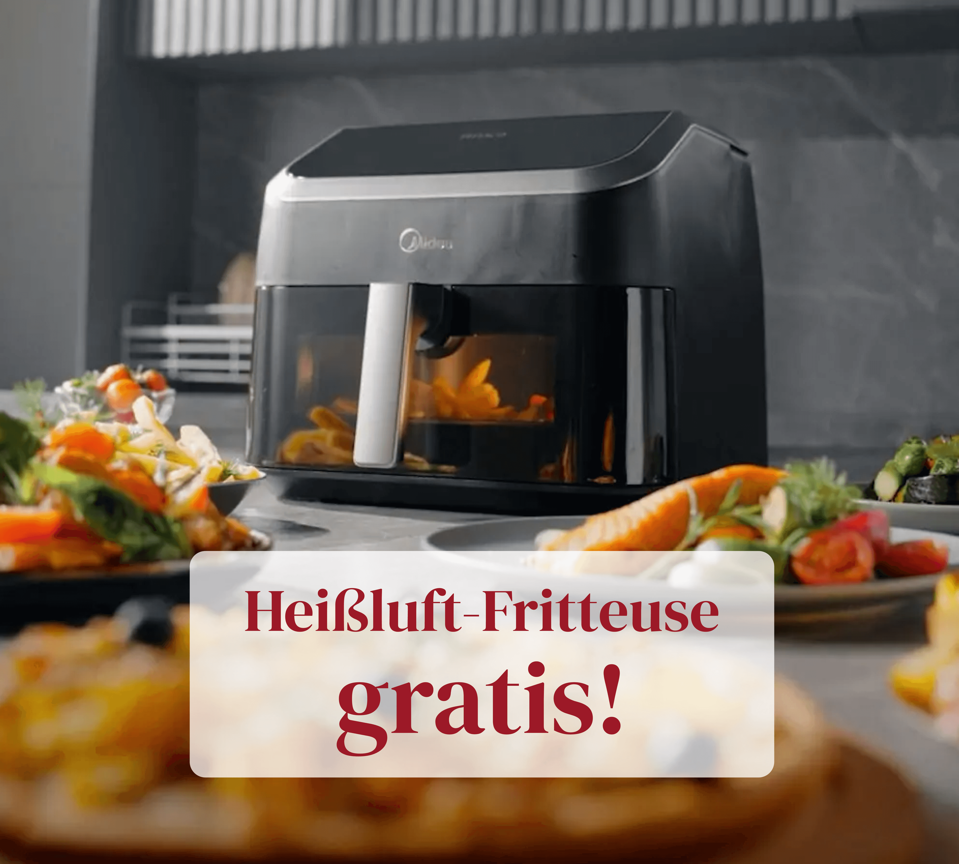 Heißluft-Fritteuse auf einer Küchenarbeitsplatte mit frisch zubereitetem Gemüse und dem Hinweis, dass sie gratis dazu gibt