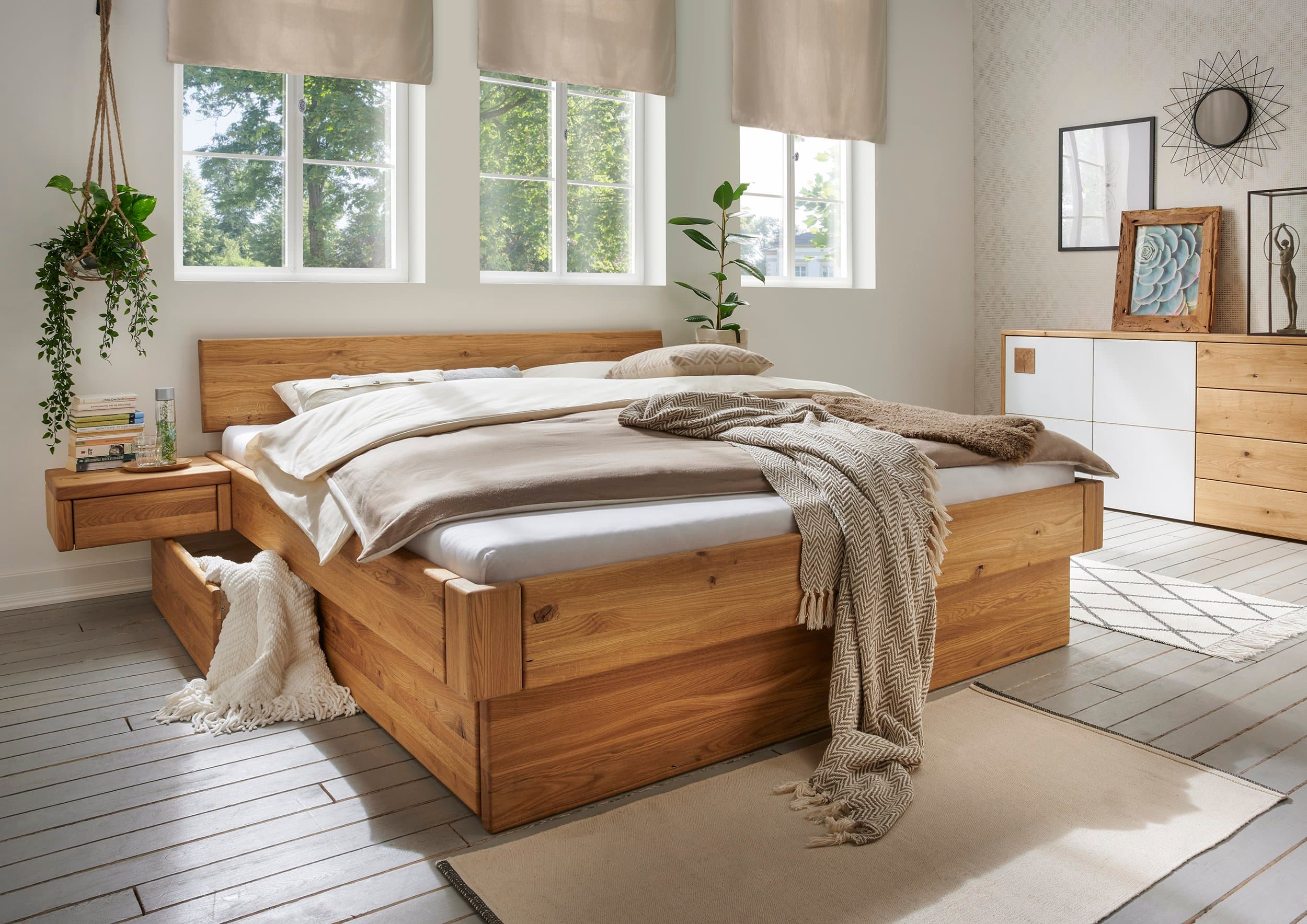 Helles Schlafzimmer mit Massivholzbett, passenden Möbeln und natürlicher Dekoration.