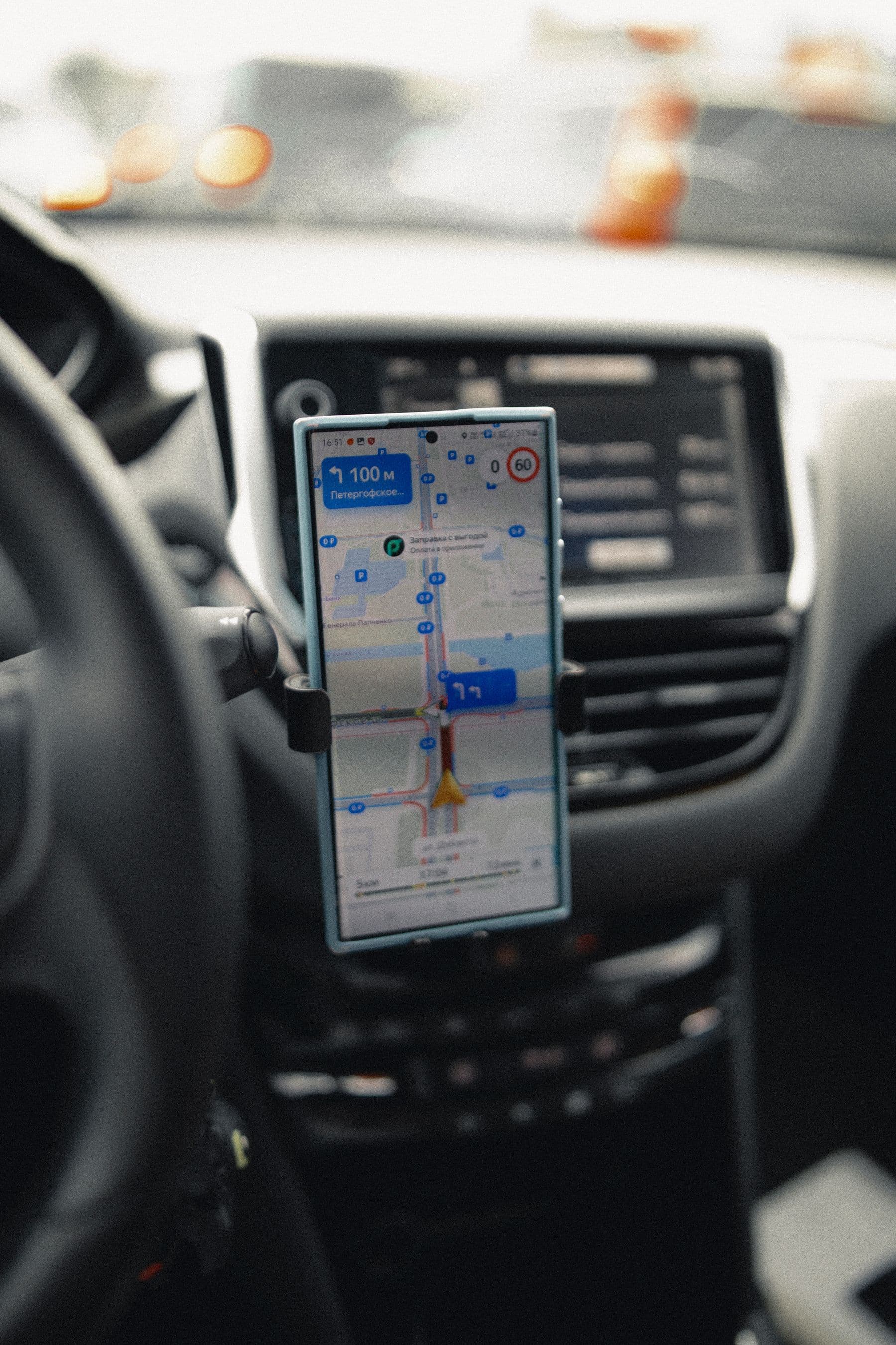Smartphone mit Navigations-Karte in der Halterung am Lenkrad eines Autos