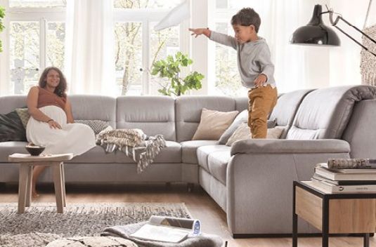 Wohnzimmer mit grauer Couch und fröhlicher Familie